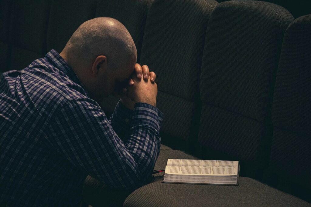 Person sitting alone in darkness while battling repeated sin and shame. Word Anchored